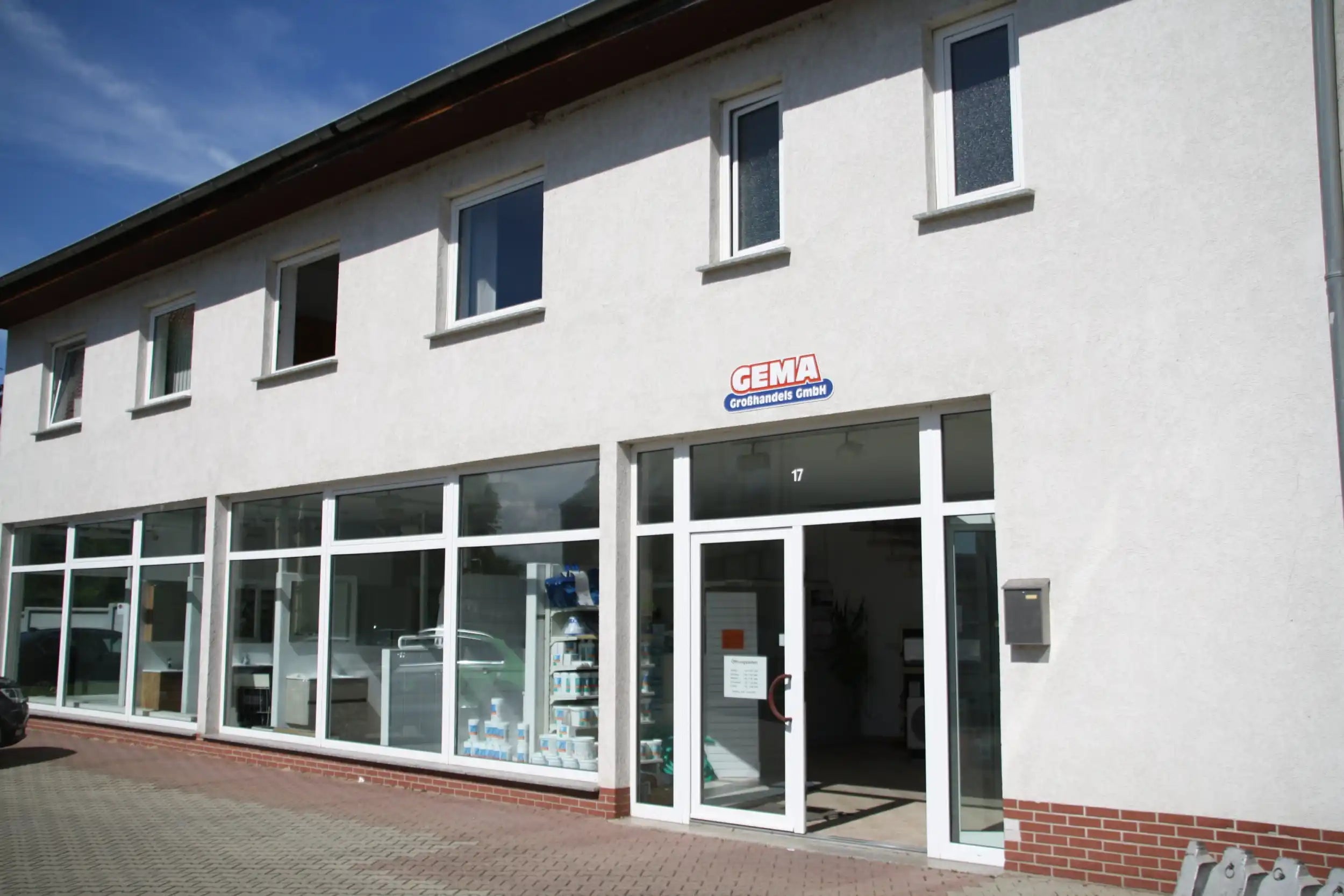 Zweistöckiges weißes Gebäude mit Schaufenstern.